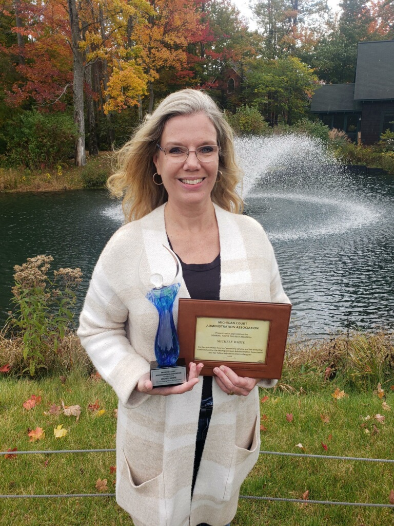 Michele White outside holding her "Soaring Above the Rest Award” from the Michigan Court Administration Association 
